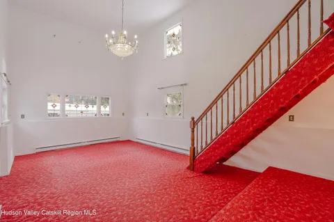 a view of an empty room with chandelier fan and wooden floor