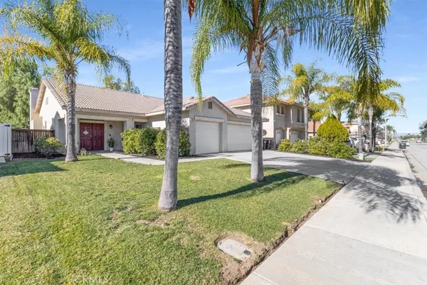 a view of a house with a yard and palm trees
