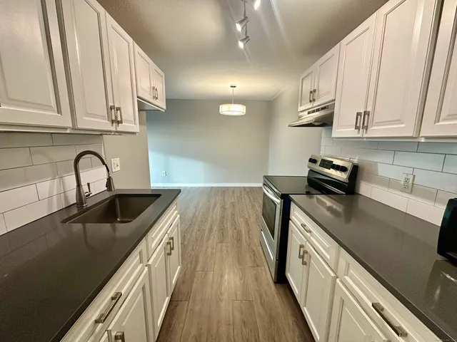 a kitchen with stainless steel appliances granite countertop a sink a stove and cabinets