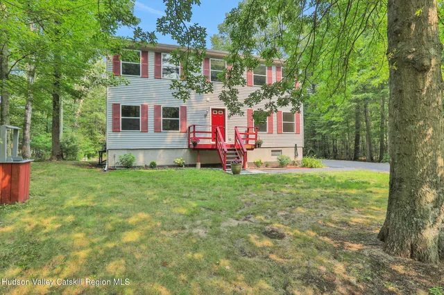 a front view of house with yard and trees in the background