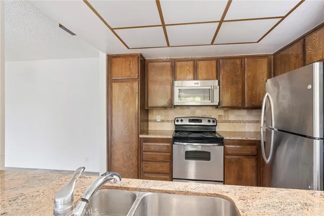 a kitchen with granite countertop a refrigerator stove and sink