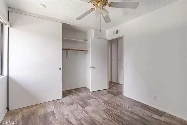 an empty room with a ceiling fan and wooden floor
