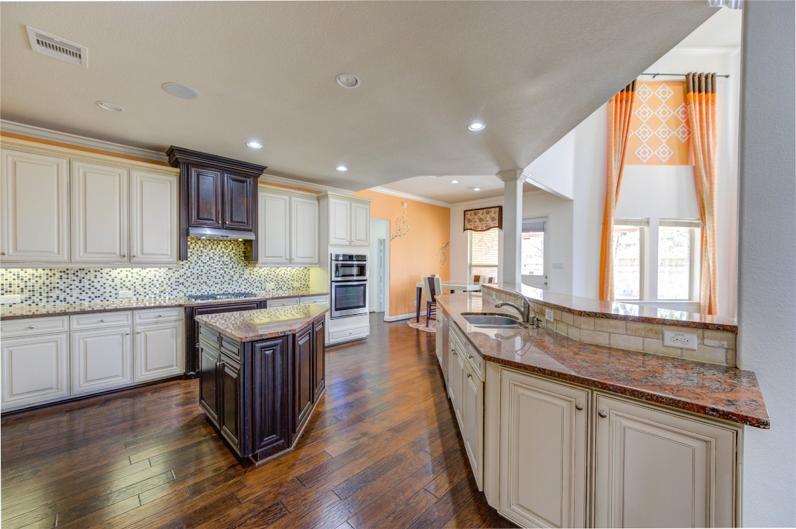 3806 Sims Pointe Court Fulshear, TX 77441 - Photo 11 of 50 a kitchen with center island wooden floor wooden floor and stainless steel appliances