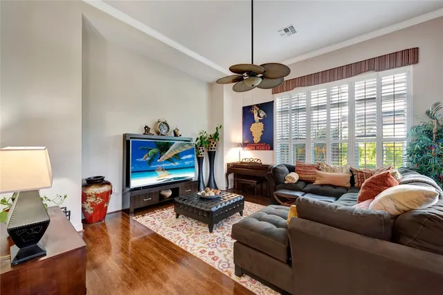 a living room with furniture a ceiling fan and a flat screen tv