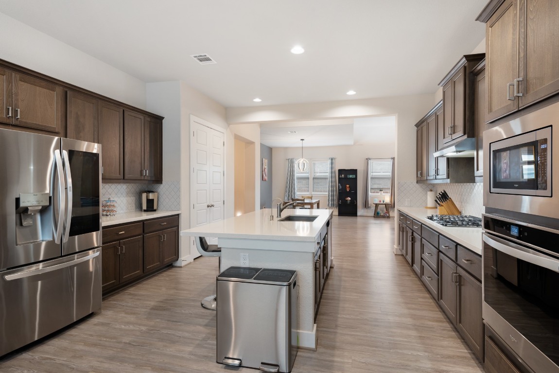 216 Emerald Garden Road San Marcos, TX 78666 - Photo 16 of 38 Kitchen featuring appliances with stainless steel finishes, backsplash, hanging light fixtures, an island with sink, and recessed lighting