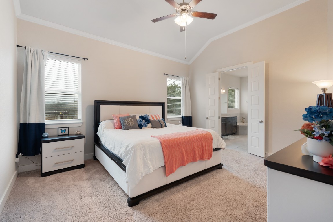 216 Emerald Garden Road San Marcos, TX 78666 - Photo 18 of 38 Bedroom with vaulted ceiling, crown molding, ensuite bathroom, light carpet, and a ceiling fan