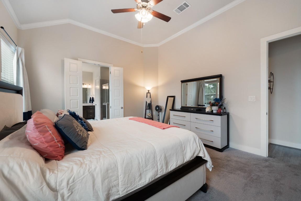 216 Emerald Garden Road San Marcos, TX 78666 - Photo 19 of 38 Carpeted bedroom with crown molding, vaulted ceiling, connected bathroom, multiple windows, and ceiling fan