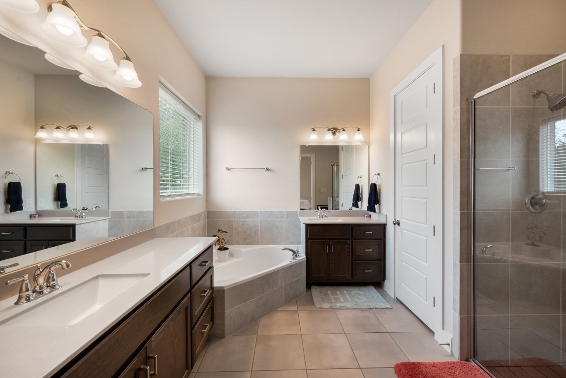 216 Emerald Garden Road San Marcos, TX 78666 - Photo 20 of 38 Bathroom with a garden tub, two vanities, light tile patterned floors, and a stall shower
