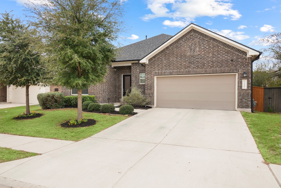 216 Emerald Garden Road San Marcos, TX 78666 - Photo 2 of 38 Ranch-style home with brick siding, concrete driveway, a garage, and roof with shingles