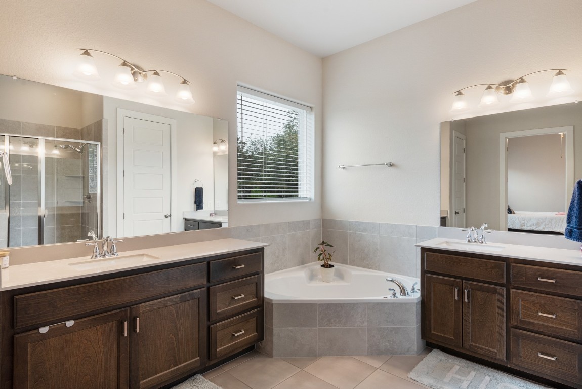 216 Emerald Garden Road San Marcos, TX 78666 - Photo 21 of 38 Ensuite bathroom with two vanities, a bath, a stall shower, and light tile patterned floors