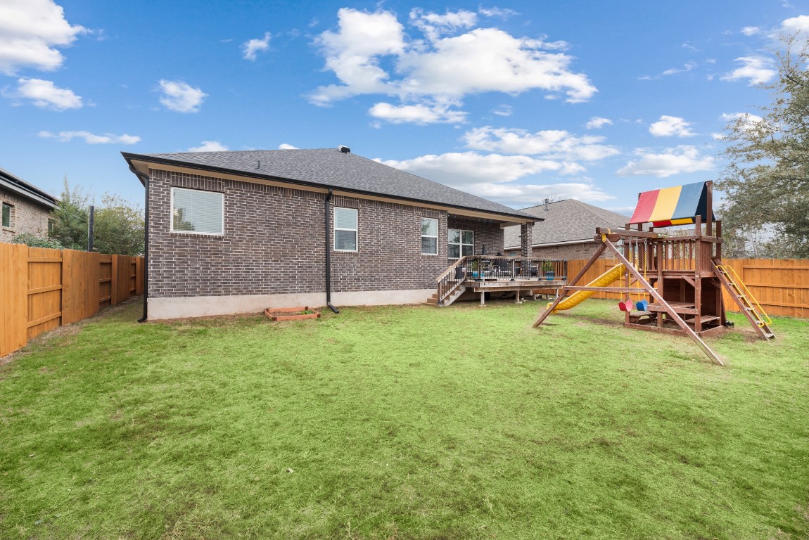 216 Emerald Garden Road San Marcos, TX 78666 - Photo 35 of 38 Rear view of house featuring a fenced backyard, a deck, a playground, brick siding, and a shingled roof