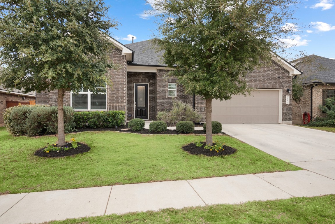 216 Emerald Garden Road San Marcos, TX 78666 - Photo 4 of 38 View of front of house with brick siding, driveway, a front yard, roof with shingles, and an attached garage