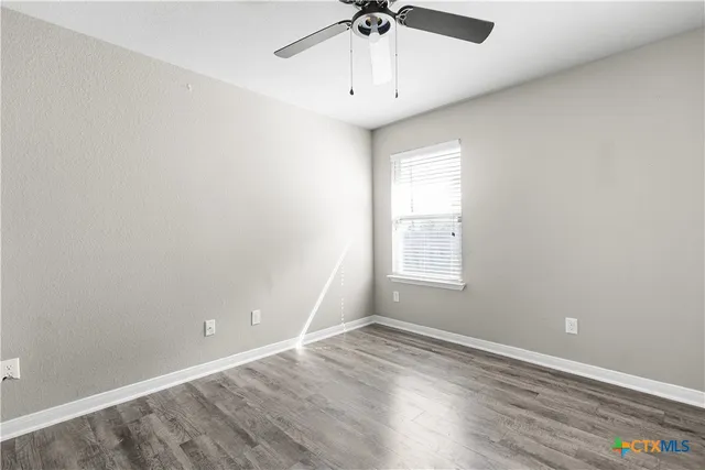 an empty room with a window and a chandelier fan