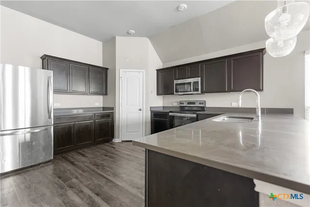 a kitchen with a refrigerator an oven a sink and cabinets