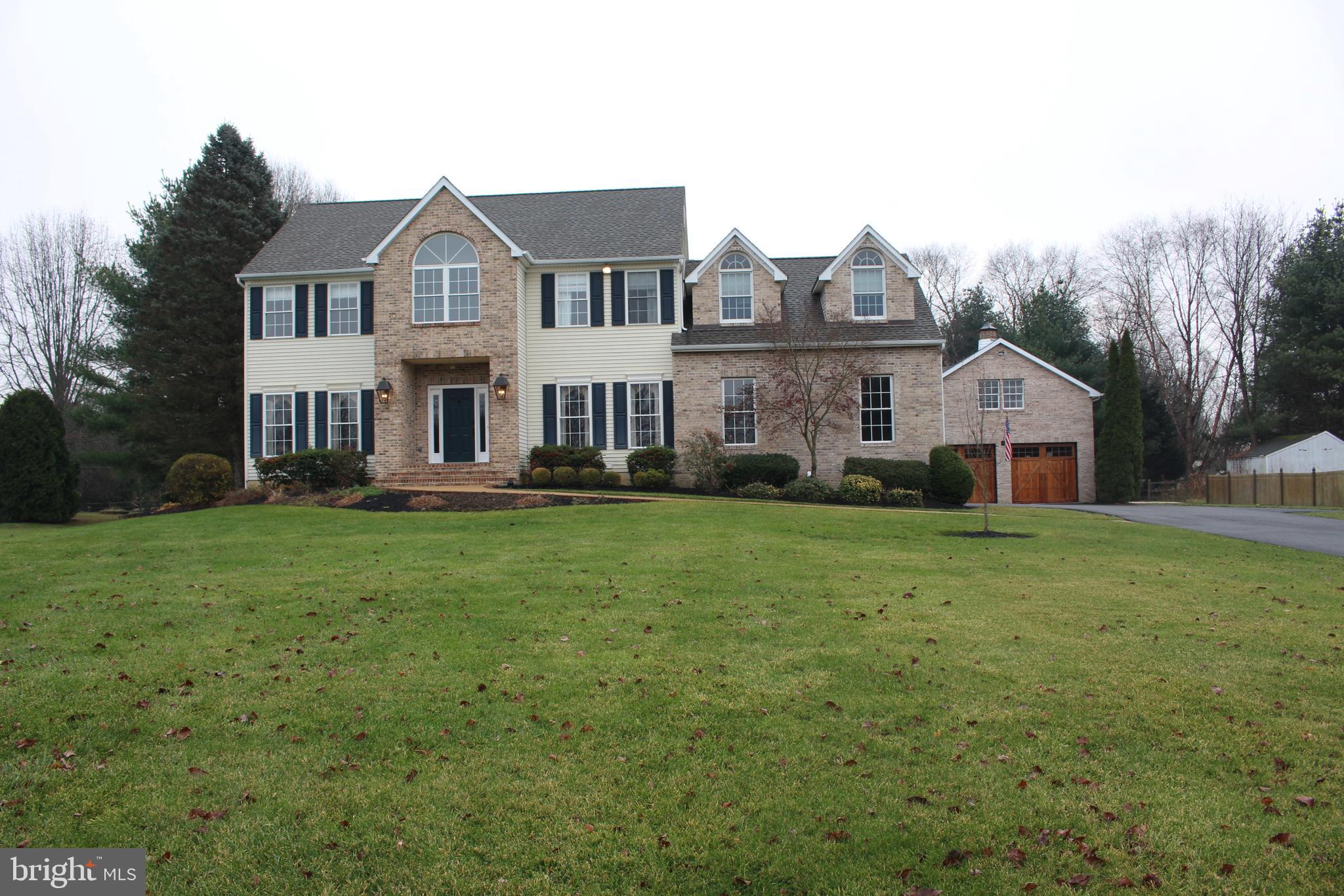 a front view of a house with a garden and trees