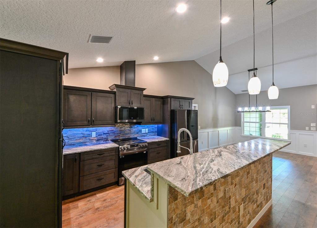 5430 West Tortuga Loop Lecanto, FL 34461 - Photo 9 of 51 a kitchen with stainless steel appliances kitchen island granite countertop a stove a sink and a wooden floors
