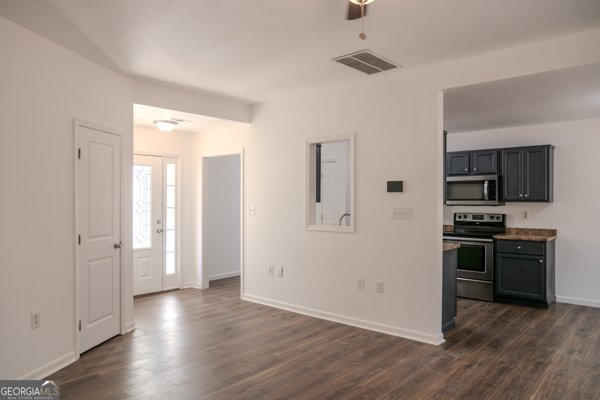 55 Corn Row Court Newnan, GA 30263 - Photo 15 of 72 an empty room with wooden floor and kitchen view