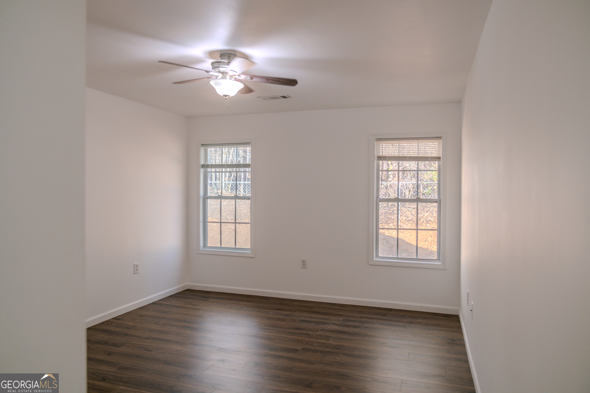55 Corn Row Court Newnan, GA 30263 - Photo 51 of 72 an empty room with wooden floor chandelier fan and windows