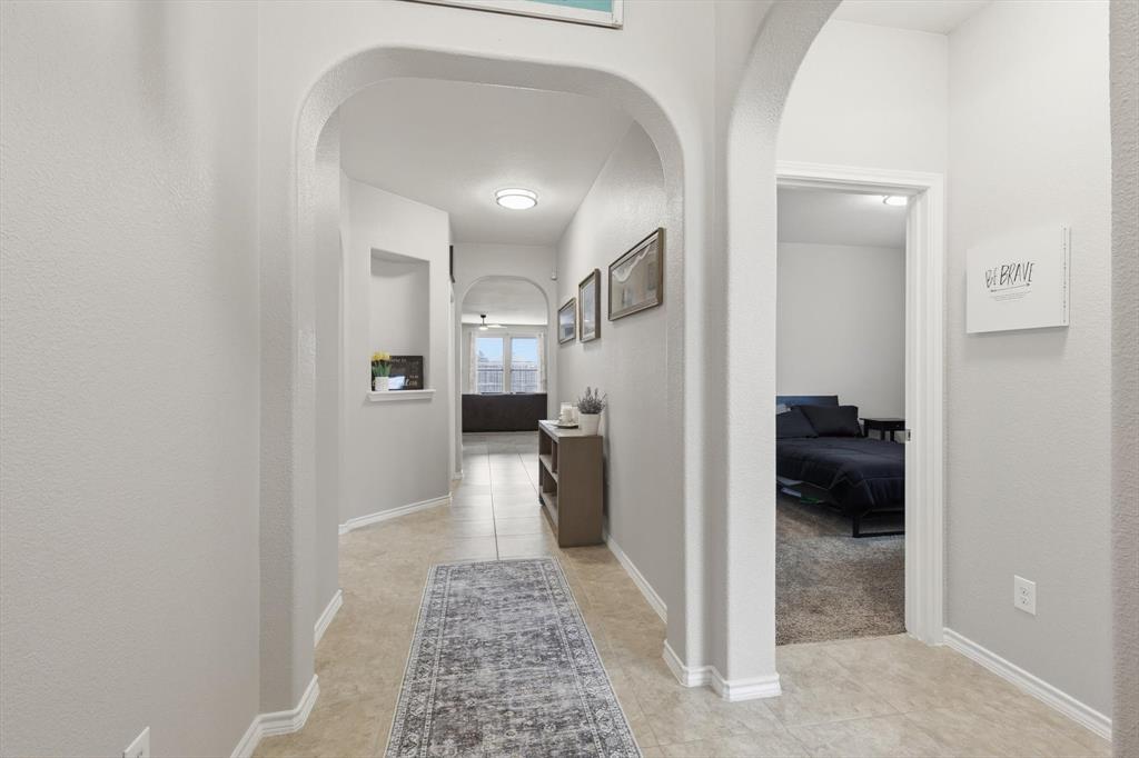 11500 Starlight Ranch Fort Worth, TX 76052 - Photo 4 of 40 Spacious hallway featuring arched doorways, light-colored walls, and tile flooring