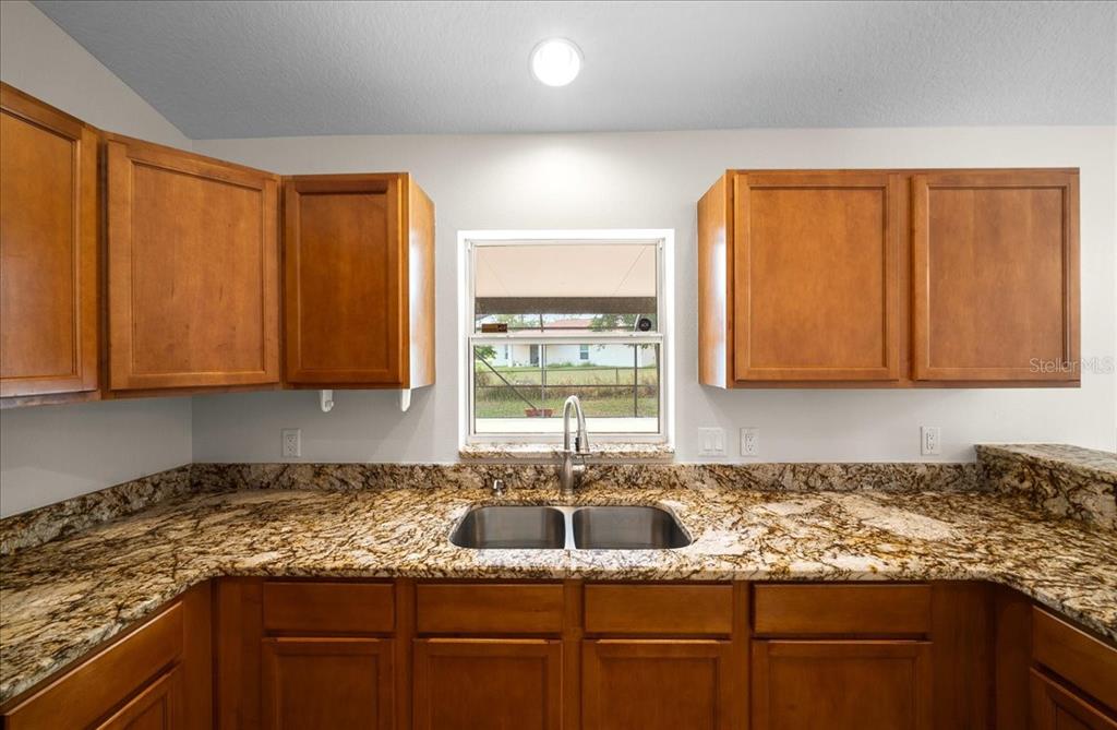 234 Locust Lane Ocala, FL 34472 - Photo 48 of 71 a kitchen with granite countertop wooden cabinets a sink and a window
