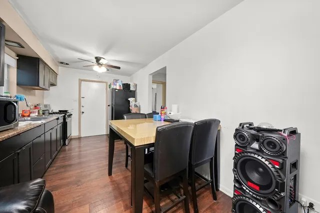 a kitchen with stainless steel appliances granite countertop a refrigerator a sink dishwasher a stove and a dining table with wooden floor