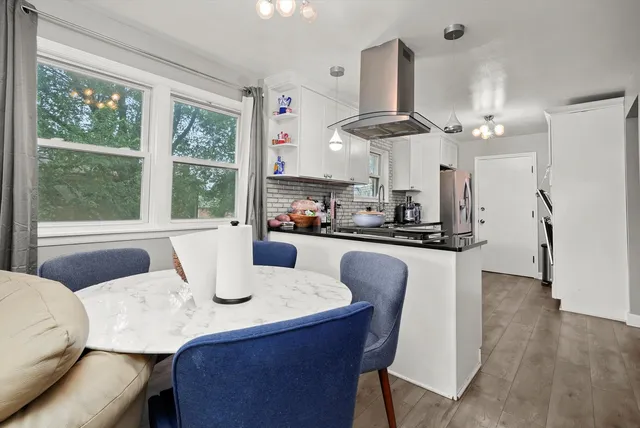 a dining room with wooden floor a chandelier a glass table and chairs
