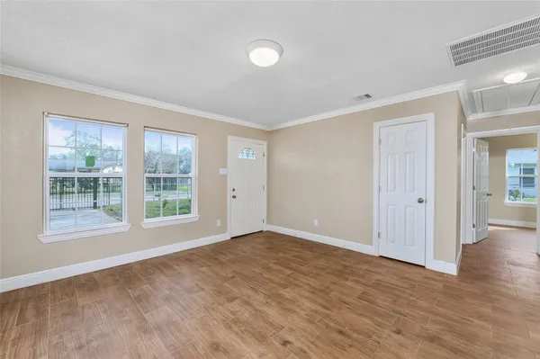 a view of an empty room with wooden floor and a window
