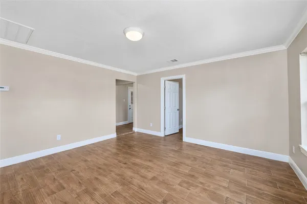 a view of an empty room with wooden floor and entryway