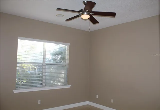 an empty room with a ceiling fan and carpet