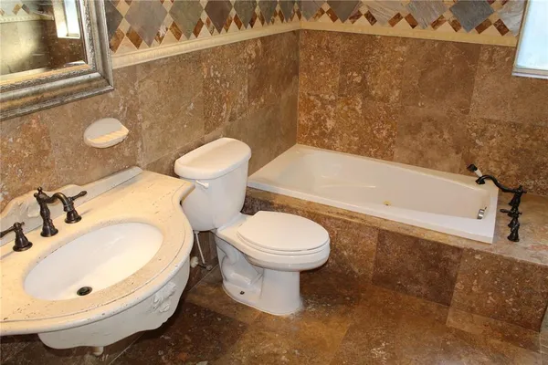 a bathroom with a tub sink and mirror