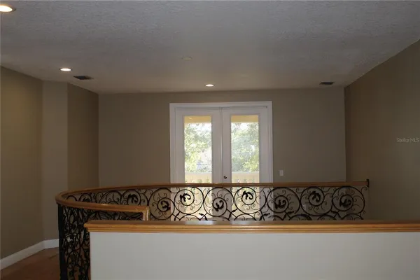a view of an empty room with wooden floor and a chandelier fan