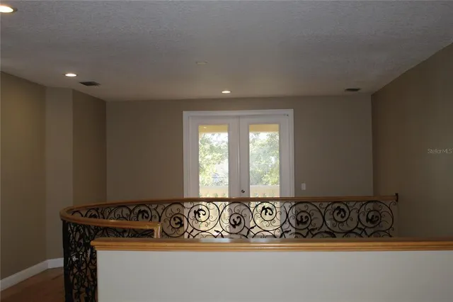 a view of an empty room with wooden floor and a chandelier fan