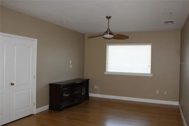 a view of an empty room with wooden floor and a window