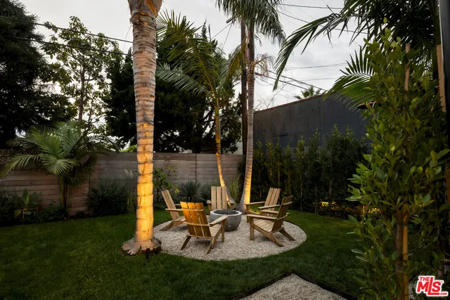 a view of a backyard with a fountain plants and a large tree
