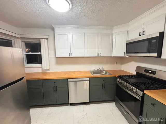 a kitchen with stainless steel appliances a sink dishwasher a stove top oven a refrigerator and cabinets