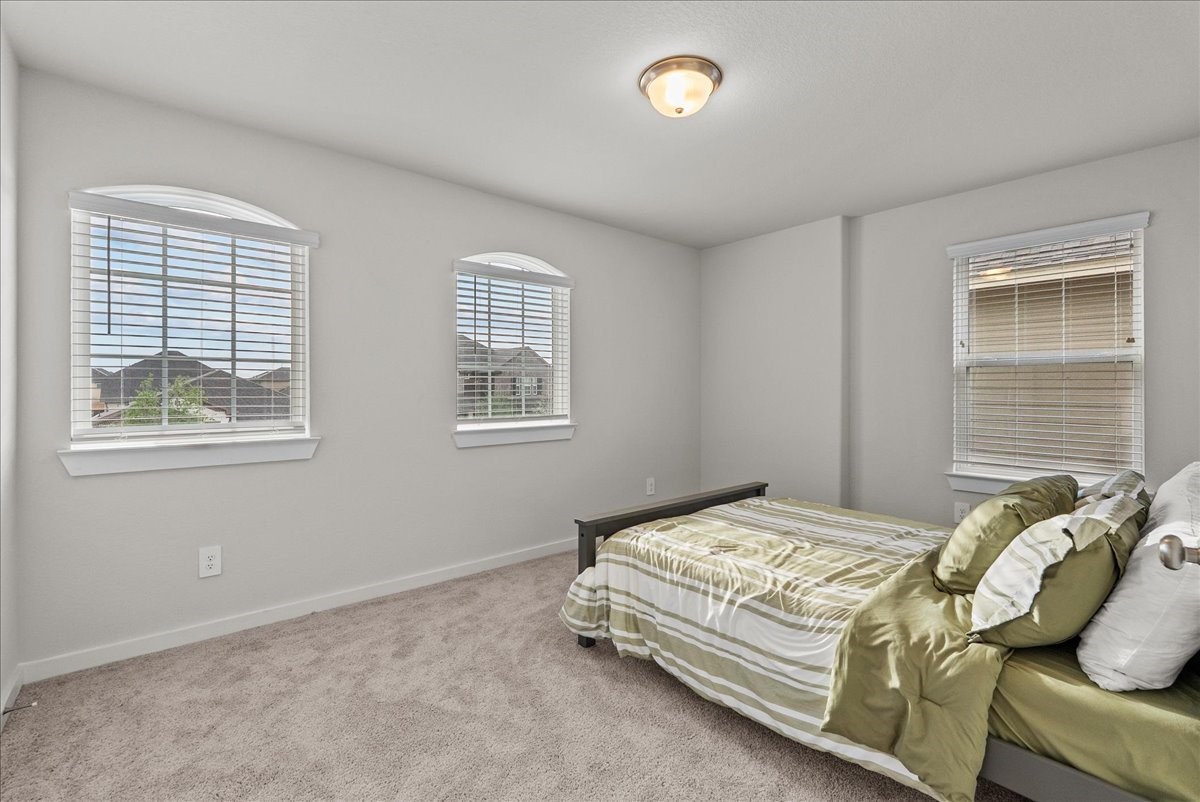 10831 Bodie Hls Drive Rosharon, TX 77583 - Photo 29 of 46 The second secondary bedroom features a unique layout with three windows, allowing abundant natural light.