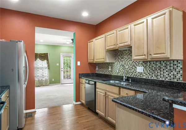 a kitchen with stainless steel appliances granite countertop a sink a stove and a refrigerator