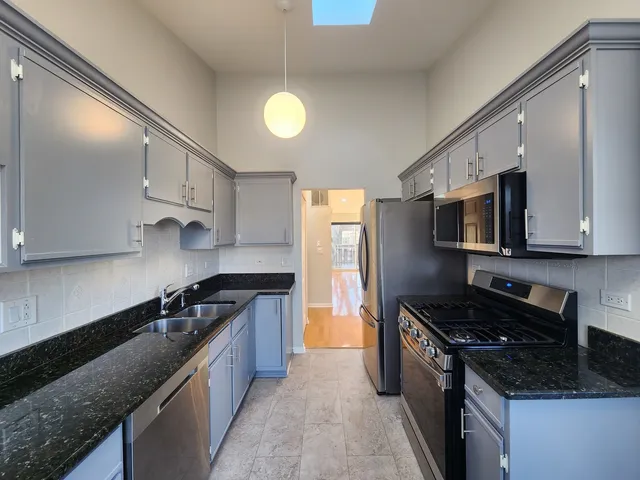 a kitchen with stainless steel appliances granite countertop a stove and a refrigerator with white cabinets