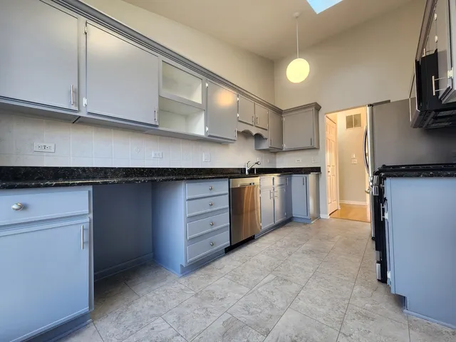 a kitchen with stainless steel appliances granite countertop a stove a sink and a refrigerator