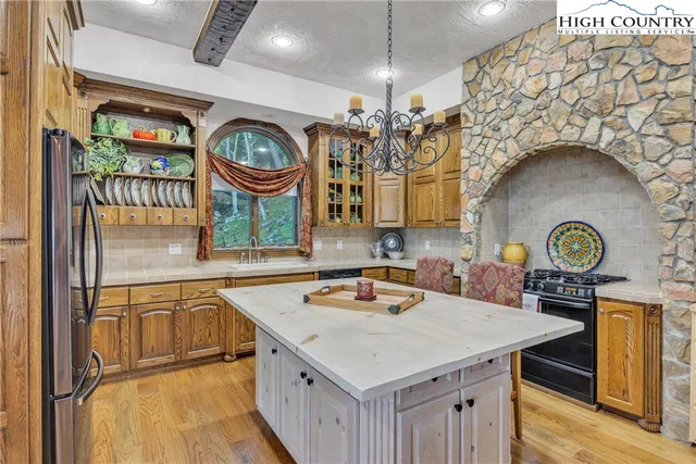 a kitchen with stainless steel appliances granite countertop a table chairs and a refrigerator