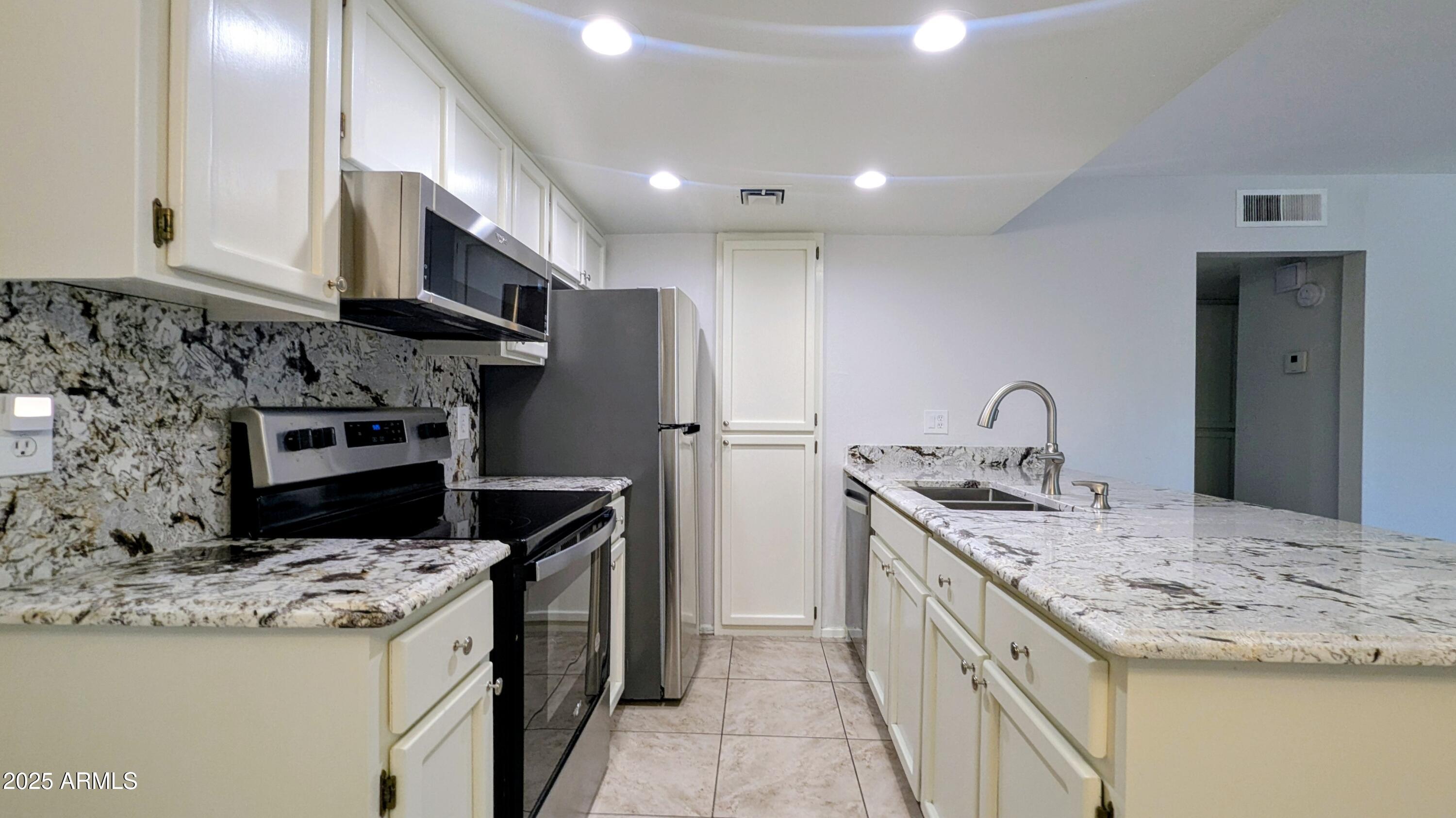 2228 East Campbell Avenue, Unit 234 Phoenix, AZ 85016 - Photo 5 of 18 a kitchen with stainless steel appliances granite countertop a sink stove and refrigerator