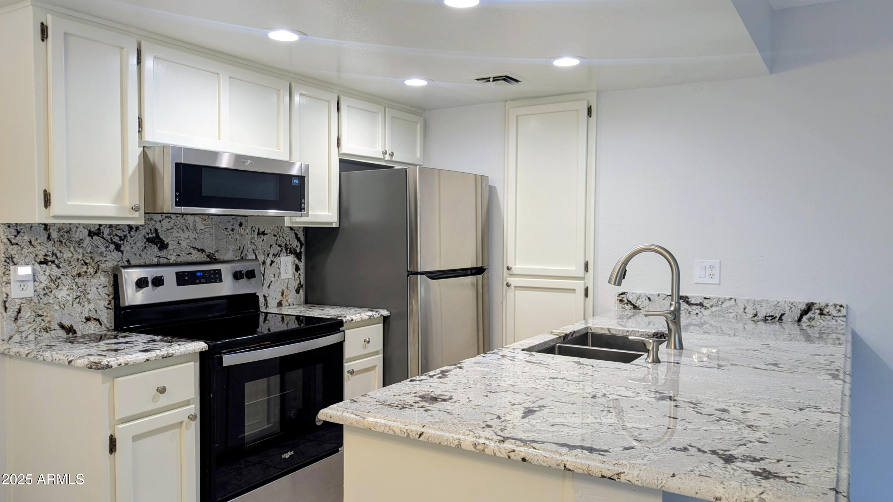2228 East Campbell Avenue, Unit 234 Phoenix, AZ 85016 - Photo 6 of 18 a kitchen with kitchen island a sink stainless steel appliances and cabinets