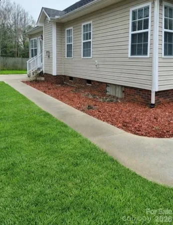 a view of a house with a yard and large tree