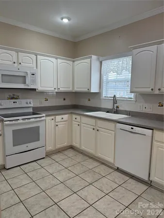 a kitchen with a sink white cabinets and white appliances