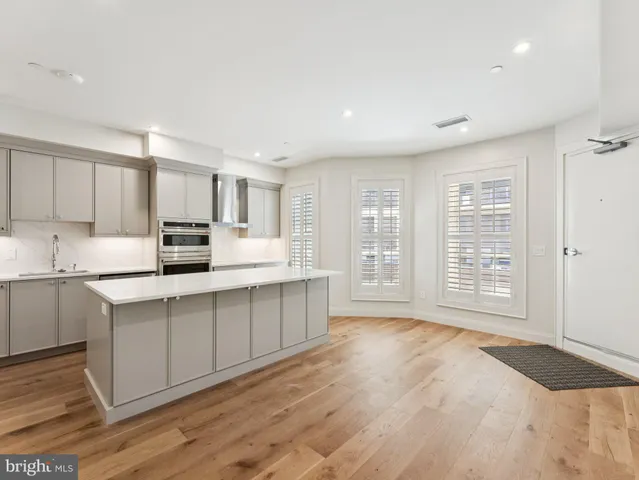 a kitchen with stainless steel appliances a sink cabinets and wooden floor