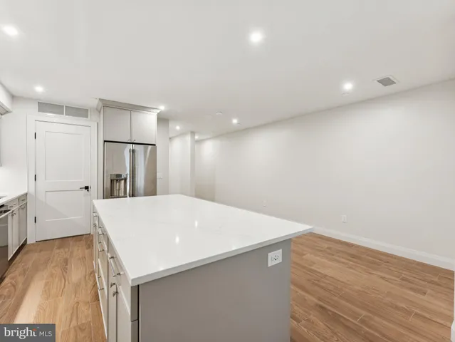 a large white kitchen with wooden floor and a sink