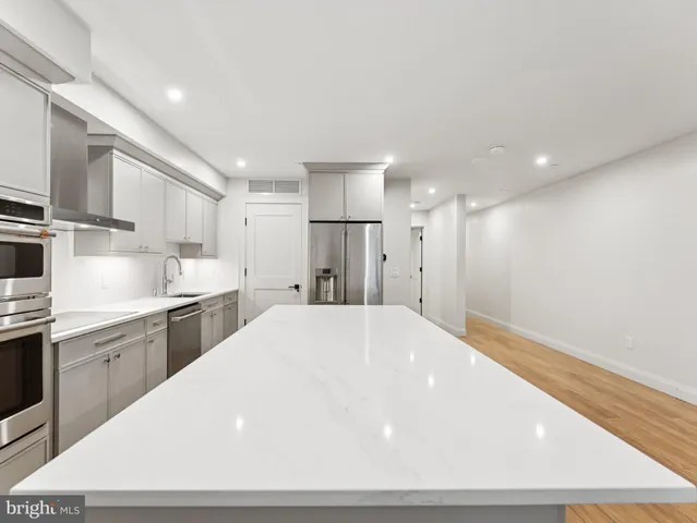 a large white kitchen with kitchen island a sink stainless steel appliances and cabinets