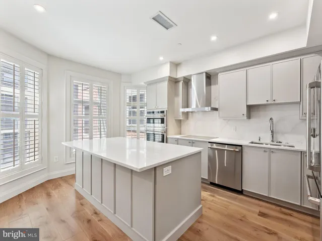 a kitchen with stainless steel appliances granite countertop a sink and dishwasher a stove top oven with wooden floor