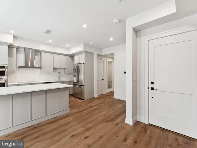 a open kitchen with white cabinets and wooden floor