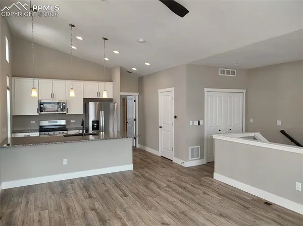 a large kitchen with stainless steel appliances a large counter top a sink a stove and a refrigerator